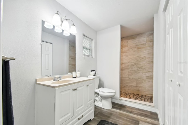 bathroom featuring a tile shower, vanity, toilet, and hardwood / wood-style flooring