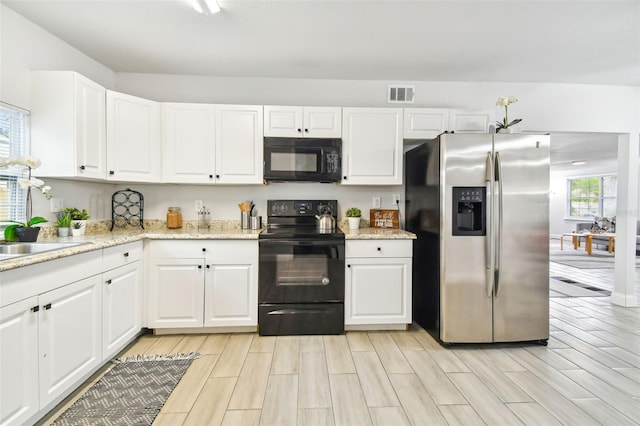 kitchen with black appliances, white cabinetry, and light hardwood / wood-style flooring