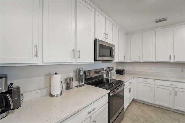 kitchen with light stone counters, white cabinetry, and appliances with stainless steel finishes