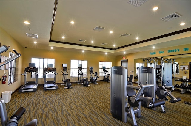 gym with a raised ceiling and dark colored carpet