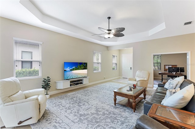 living room with ceiling fan and a raised ceiling