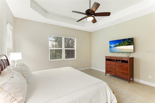 bedroom with a tray ceiling, ceiling fan, and light tile patterned floors