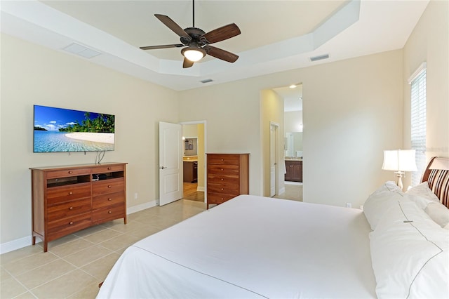 tiled bedroom featuring ceiling fan, a raised ceiling, and ensuite bath