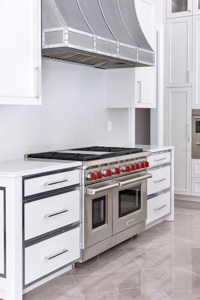 kitchen featuring white cabinetry, exhaust hood, and double oven range