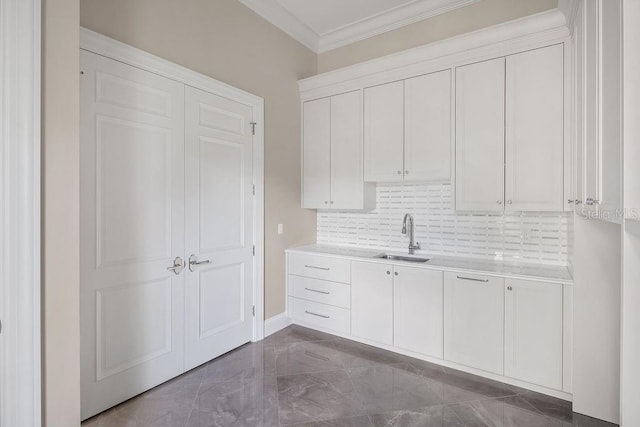 kitchen with decorative backsplash, ornamental molding, sink, and white cabinets