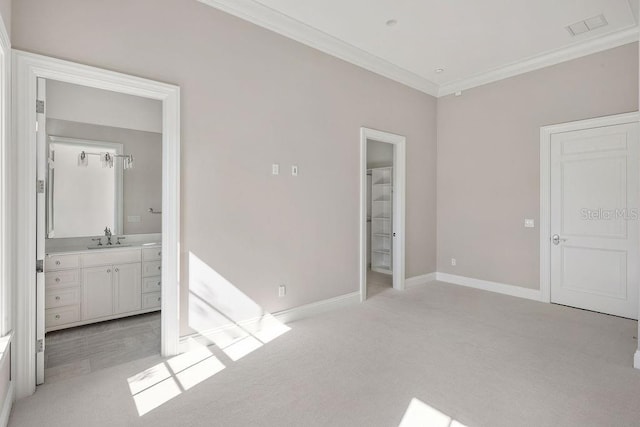 unfurnished bedroom featuring crown molding, ensuite bath, sink, and light colored carpet