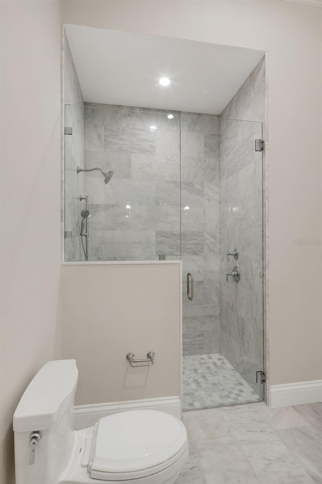 bathroom featuring a shower with door and toilet