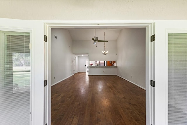 unfurnished living room featuring dark hardwood / wood-style flooring, an inviting chandelier, and lofted ceiling