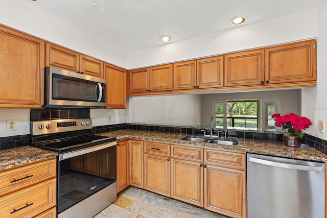 kitchen featuring appliances with stainless steel finishes, dark stone countertops, and sink