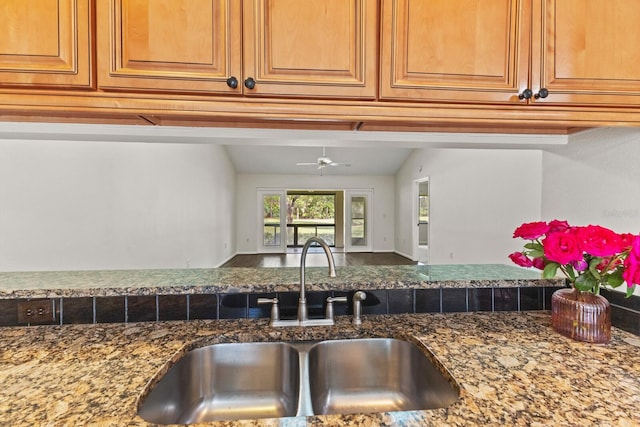 kitchen with ceiling fan, lofted ceiling, sink, and dark stone counters