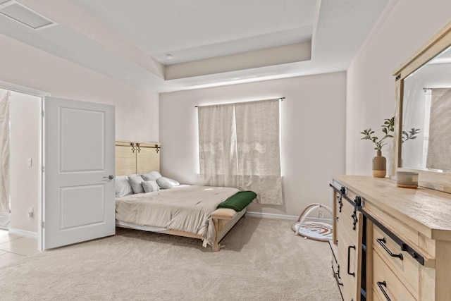 bedroom with a tray ceiling and light colored carpet