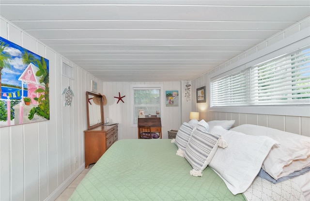 bedroom featuring multiple windows and wooden walls