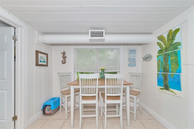 dining room featuring wood walls and light tile patterned floors