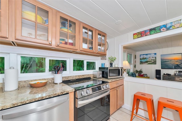 kitchen featuring appliances with stainless steel finishes, light stone counters, and light tile patterned floors