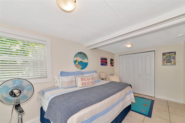 bedroom with a closet, a textured ceiling, and light tile patterned floors