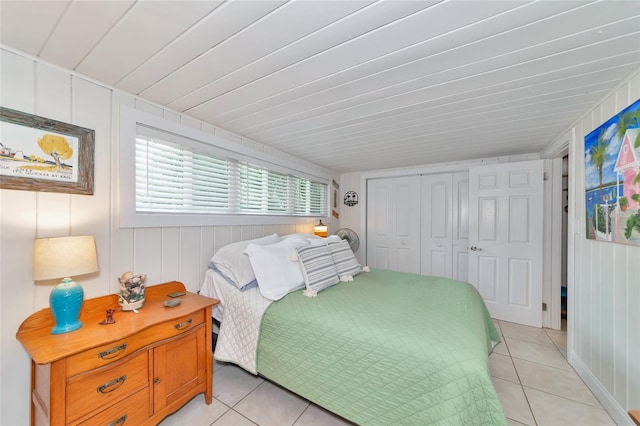 tiled bedroom featuring wood walls and a closet