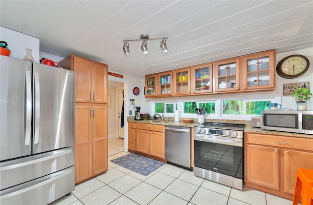 kitchen featuring light stone countertops, sink, light tile patterned flooring, and stainless steel appliances