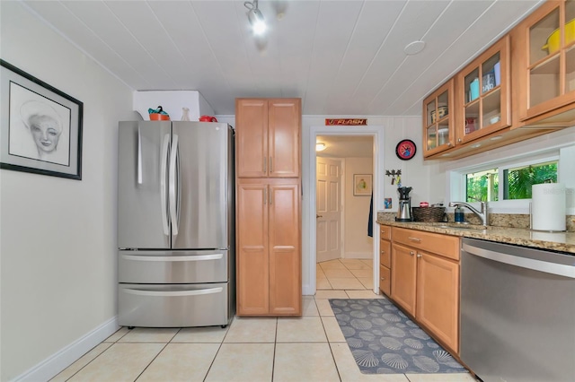 kitchen featuring stainless steel appliances, light tile patterned floors, light stone counters, and sink