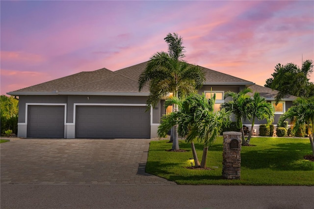 view of front of home with a garage and a lawn