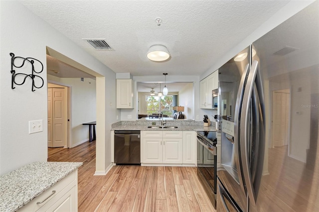 kitchen featuring light stone counters, white cabinets, black appliances, light hardwood / wood-style flooring, and sink