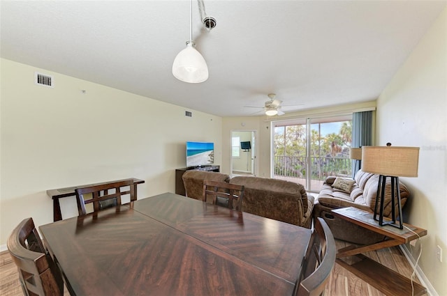 dining room featuring baseboards, visible vents, wood finished floors, and a ceiling fan