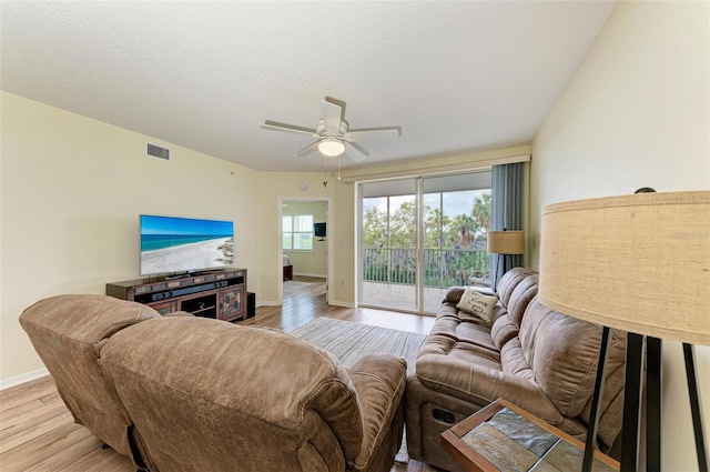 living room featuring wood finished floors, baseboards, ceiling fan, and visible vents