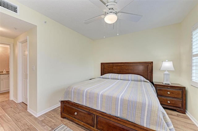 bedroom with ceiling fan, light wood-type flooring, and ensuite bath