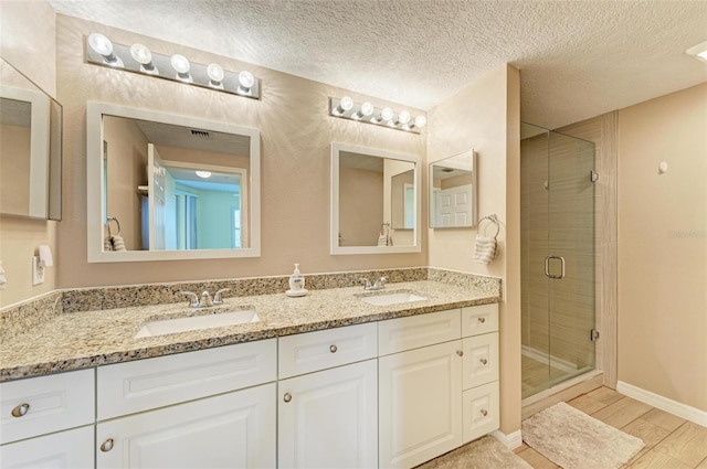 bathroom with a stall shower, wood finished floors, a sink, and a textured ceiling
