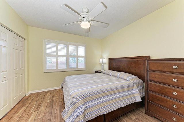 bedroom featuring a closet, baseboards, light wood-style floors, and ceiling fan