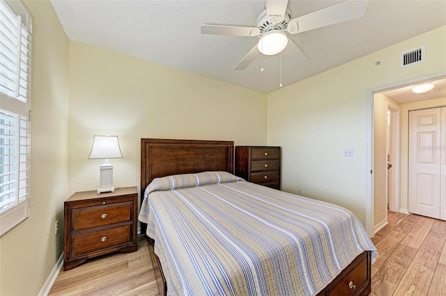bedroom with a ceiling fan, baseboards, light wood finished floors, and visible vents