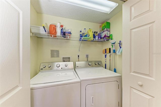 laundry room with washing machine and clothes dryer, a textured ceiling, and laundry area