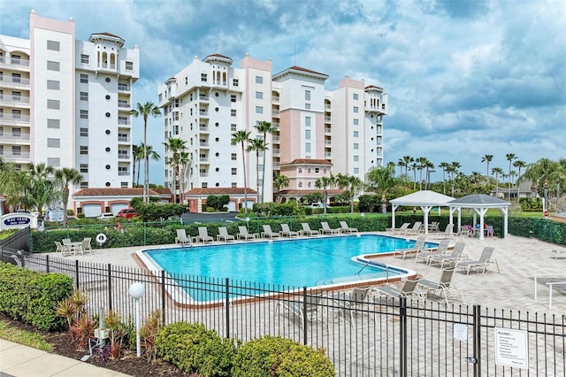 community pool with a patio area, a gazebo, and fence
