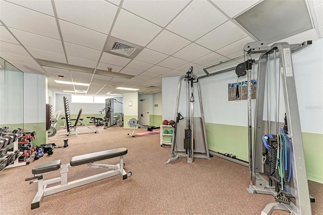 exercise room featuring a paneled ceiling and light colored carpet