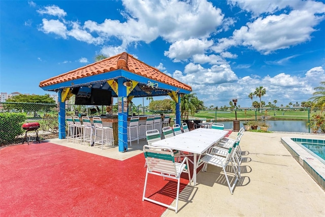 exterior space featuring a patio, a water view, a gazebo, an outdoor bar, and a swimming pool