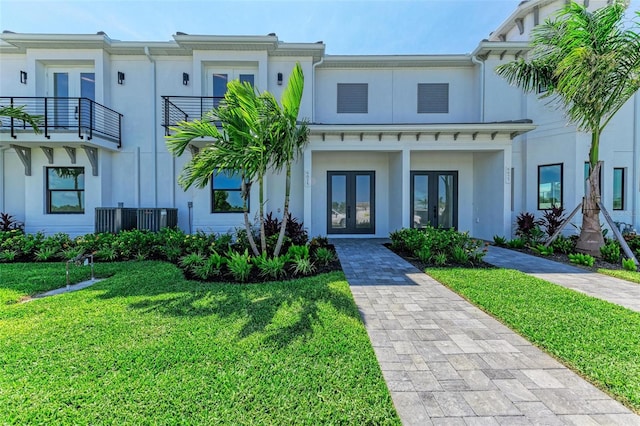 view of front of property featuring cooling unit, a balcony, french doors, and a front yard