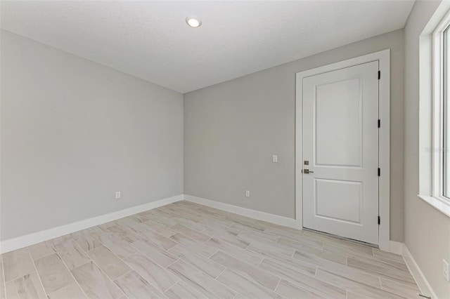 unfurnished room with a textured ceiling and light hardwood / wood-style floors