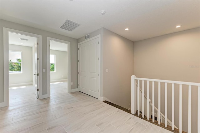 hall with a textured ceiling and light hardwood / wood-style flooring