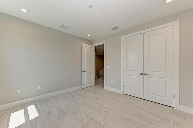 unfurnished bedroom with a textured ceiling, light hardwood / wood-style flooring, and a closet