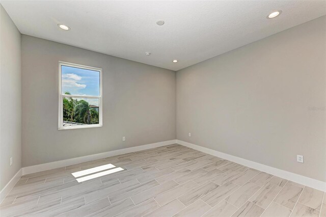 spare room with light wood-type flooring and a textured ceiling