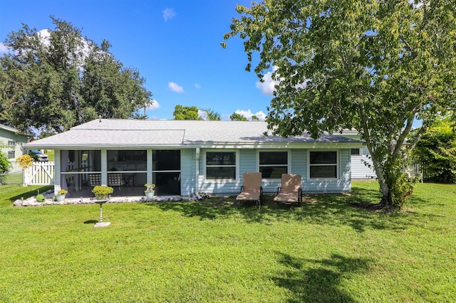 rear view of property with a lawn and a sunroom