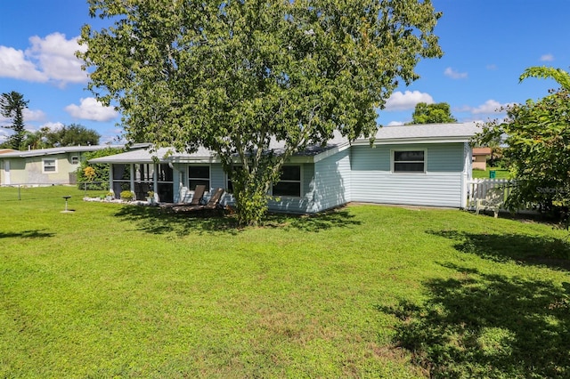 back of property with a lawn and a sunroom