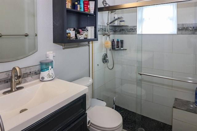 bathroom with backsplash, vanity, a shower with shower door, and toilet