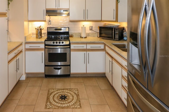 kitchen with appliances with stainless steel finishes, decorative backsplash, light tile patterned flooring, white cabinetry, and light stone counters