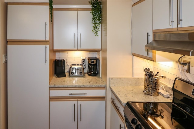 kitchen featuring white cabinets, light stone countertops, black electric range oven, and decorative backsplash