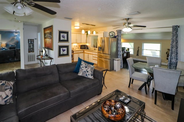 living room with ceiling fan and a textured ceiling