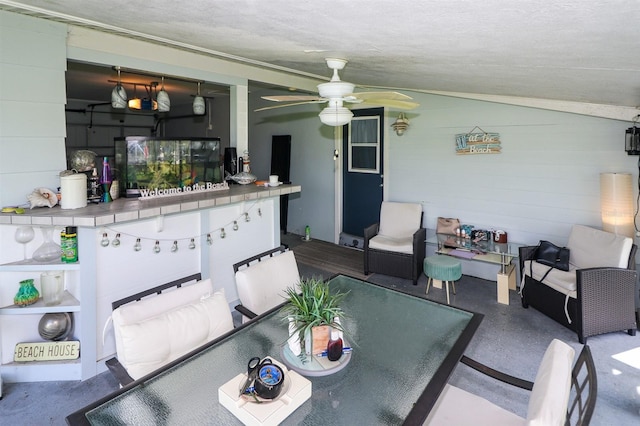 dining area with ceiling fan, a textured ceiling, vaulted ceiling, and concrete flooring