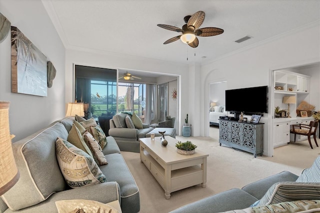 carpeted living room featuring ornamental molding and ceiling fan