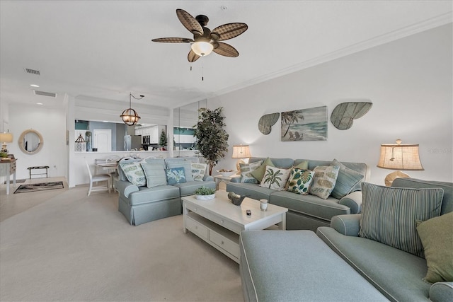 carpeted living room featuring ornamental molding and ceiling fan with notable chandelier