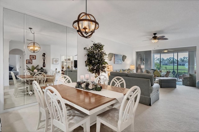 carpeted dining room featuring ceiling fan with notable chandelier, a textured ceiling, and ornamental molding