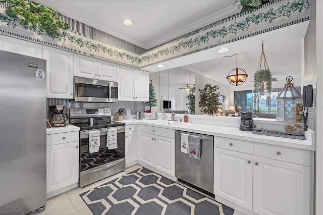 kitchen with stainless steel appliances, white cabinets, sink, crown molding, and decorative light fixtures